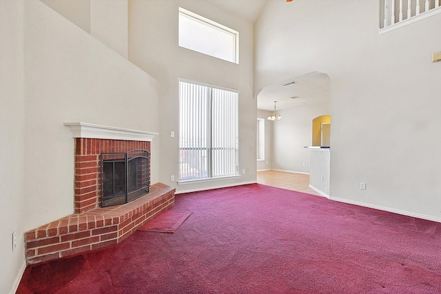 unfurnished living room featuring a high ceiling, carpet, and a brick fireplace