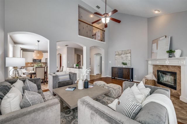 living room featuring ceiling fan, a fireplace, and high vaulted ceiling