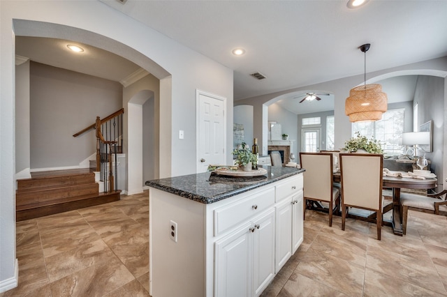 kitchen with hanging light fixtures, white cabinetry, a kitchen island, and dark stone countertops