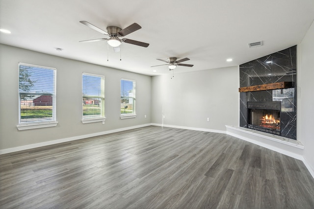 unfurnished living room featuring a premium fireplace, dark hardwood / wood-style floors, and ceiling fan