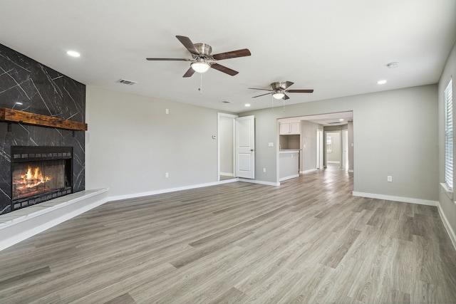 unfurnished living room featuring ceiling fan, a high end fireplace, and light hardwood / wood-style floors