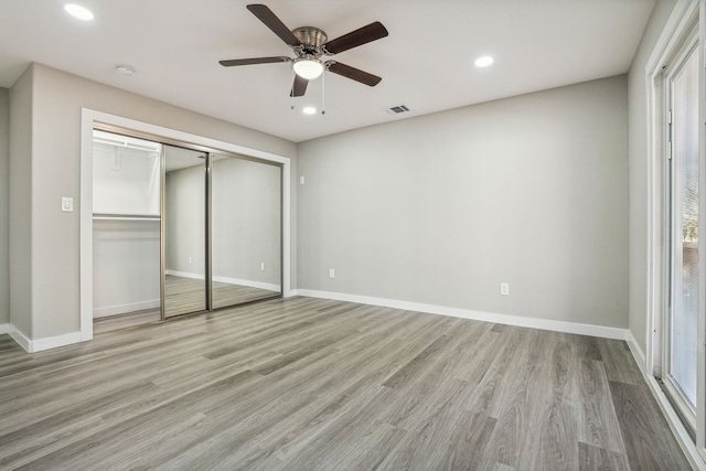 unfurnished bedroom featuring multiple windows, a closet, and light wood-type flooring