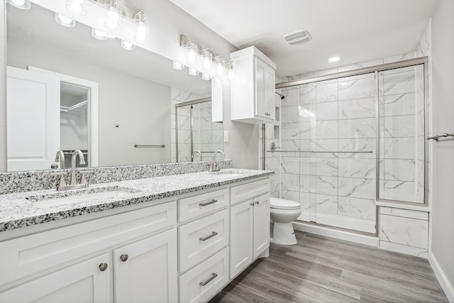 bathroom with hardwood / wood-style flooring, vanity, toilet, and an enclosed shower