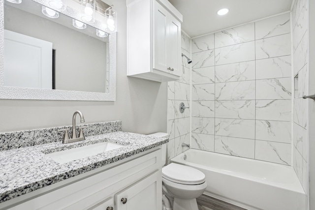 full bathroom featuring hardwood / wood-style flooring, vanity, toilet, and tiled shower / bath combo