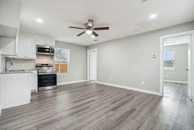 kitchen featuring appliances with stainless steel finishes, tasteful backsplash, sink, white cabinets, and light hardwood / wood-style floors