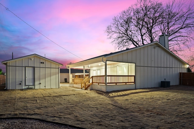 back house at dusk featuring a wooden deck and central AC unit