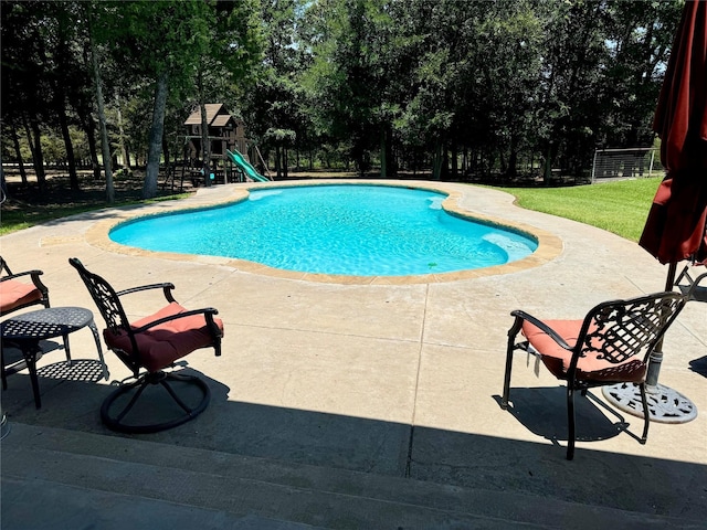 view of swimming pool with a playground and a patio area