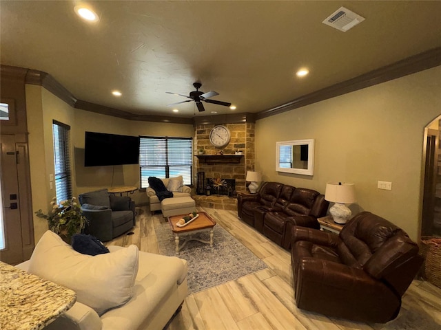 living room featuring crown molding, a fireplace, light hardwood / wood-style floors, and ceiling fan