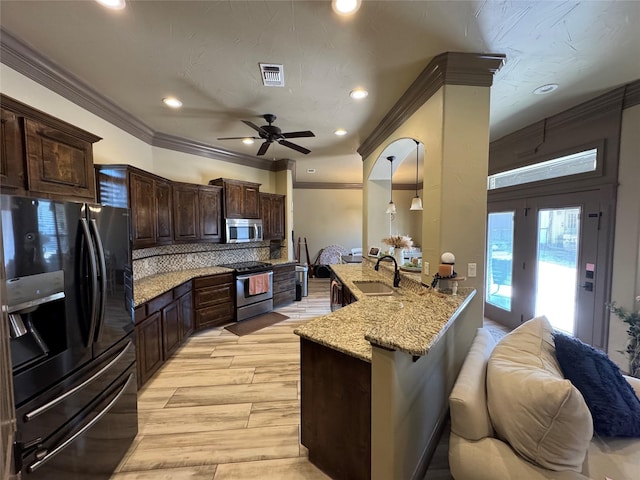 kitchen with sink, decorative light fixtures, light wood-type flooring, appliances with stainless steel finishes, and decorative backsplash