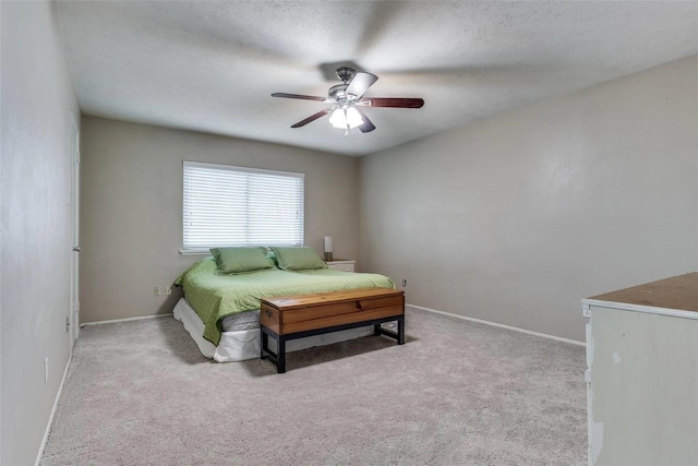 bedroom with ceiling fan, light carpet, and a textured ceiling