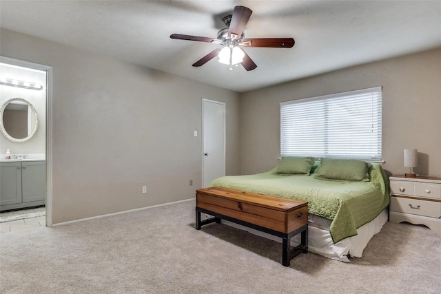 bedroom featuring ensuite bathroom, sink, light carpet, and ceiling fan