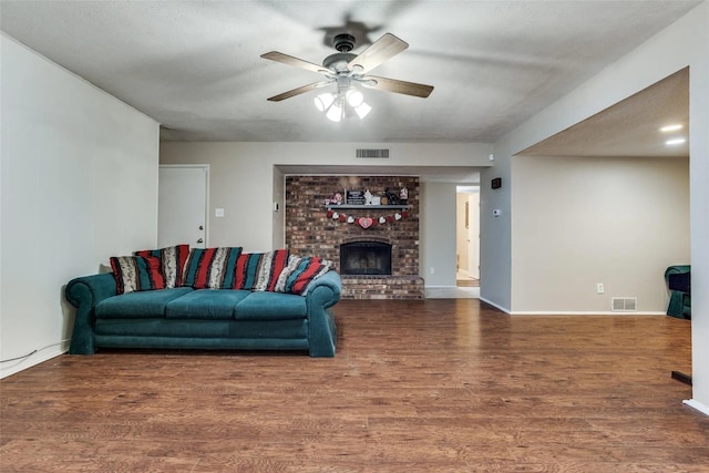 living room with ceiling fan, dark wood-type flooring, and a fireplace