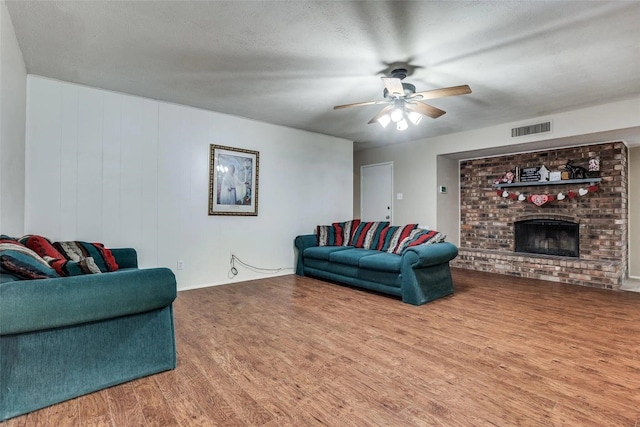 living room featuring hardwood / wood-style floors, a textured ceiling, a fireplace, and ceiling fan