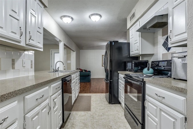 kitchen with tasteful backsplash, white cabinetry, sink, black appliances, and custom range hood