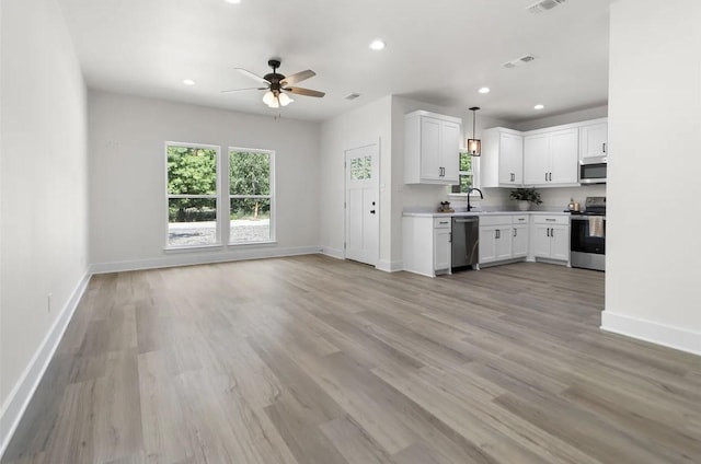 kitchen with hanging light fixtures, white cabinetry, appliances with stainless steel finishes, and sink