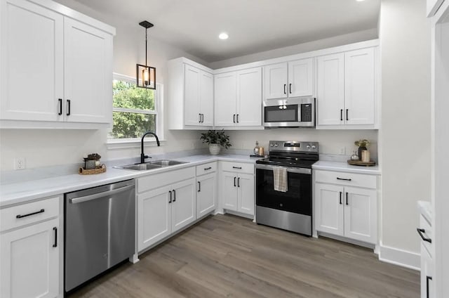 kitchen with white cabinetry, sink, wood-type flooring, and appliances with stainless steel finishes