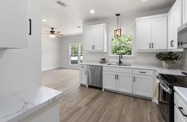 kitchen featuring appliances with stainless steel finishes, sink, pendant lighting, and white cabinets