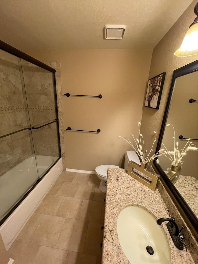 full bathroom featuring vanity, combined bath / shower with glass door, a textured ceiling, and toilet