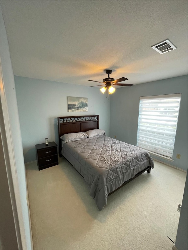 bedroom with ceiling fan, carpet, and a textured ceiling