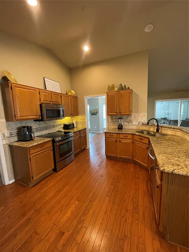 kitchen with tasteful backsplash, appliances with stainless steel finishes, sink, and light wood-type flooring