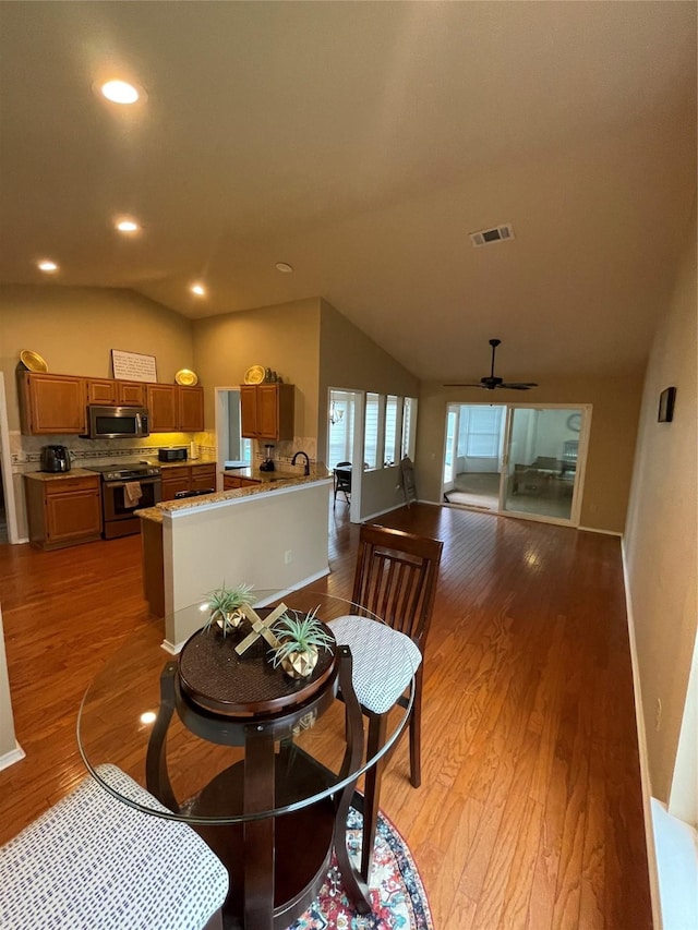 dining space featuring ceiling fan, lofted ceiling, and light wood-type flooring