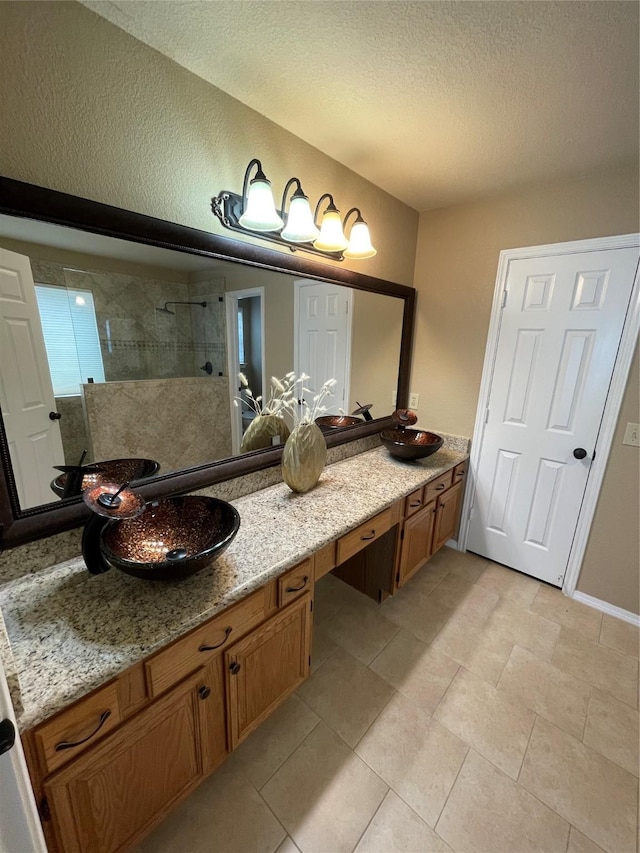 bathroom with an enclosed shower, vanity, and a textured ceiling