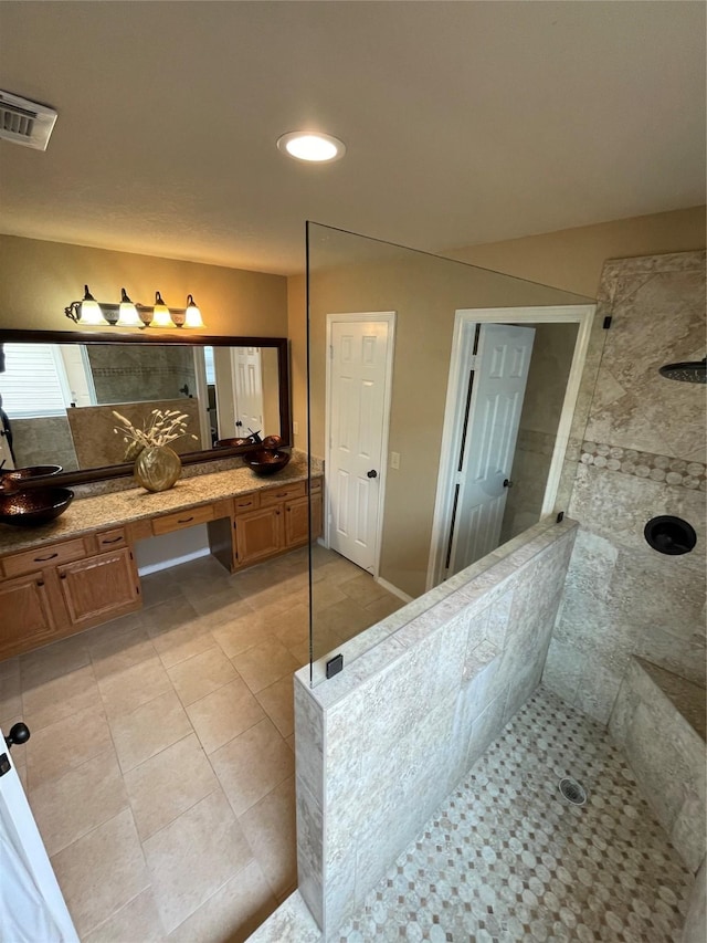 bathroom with tile patterned floors, vanity, and a tile shower