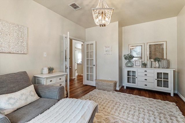 bedroom with dark hardwood / wood-style floors, an inviting chandelier, and french doors