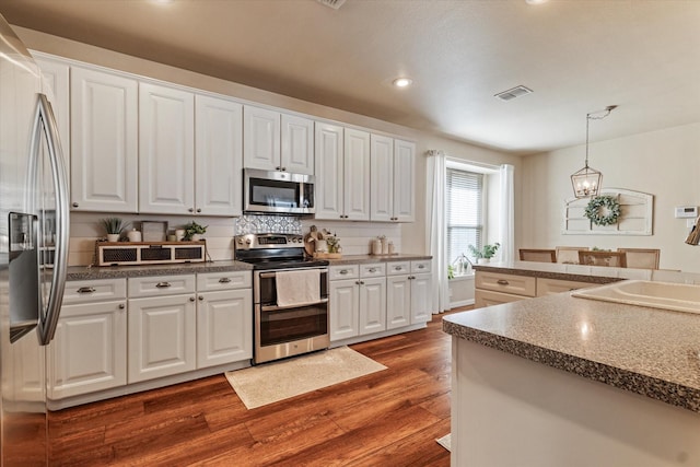 kitchen featuring white cabinetry, stainless steel appliances, dark hardwood / wood-style floors, decorative backsplash, and decorative light fixtures