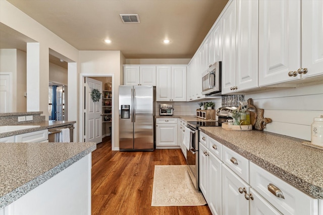 kitchen with sink, dark wood-type flooring, backsplash, stainless steel appliances, and white cabinets