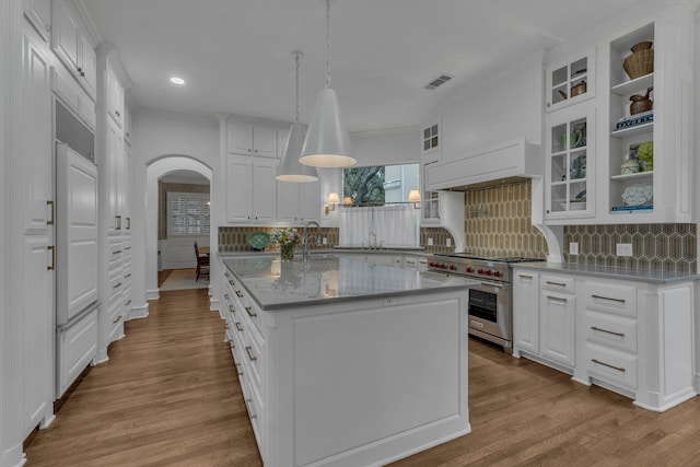 kitchen featuring white cabinetry, double oven range, a center island with sink, and pendant lighting