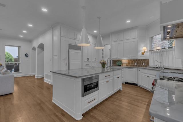 kitchen with a kitchen island, white cabinets, decorative backsplash, light stone counters, and paneled dishwasher