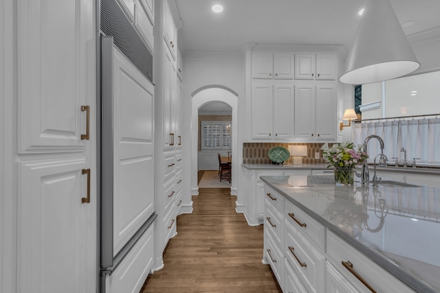 kitchen with tasteful backsplash, white cabinetry, sink, ornamental molding, and dark wood-type flooring