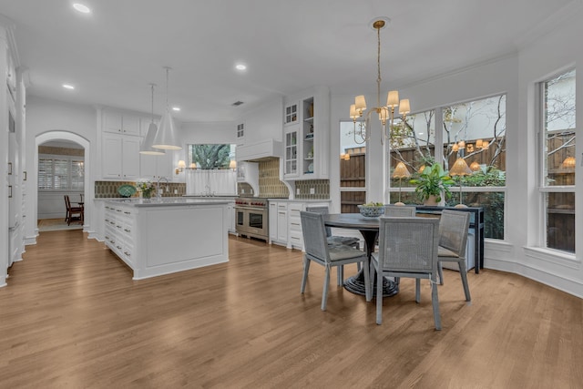 dining room featuring an inviting chandelier, crown molding, sink, and light wood-type flooring