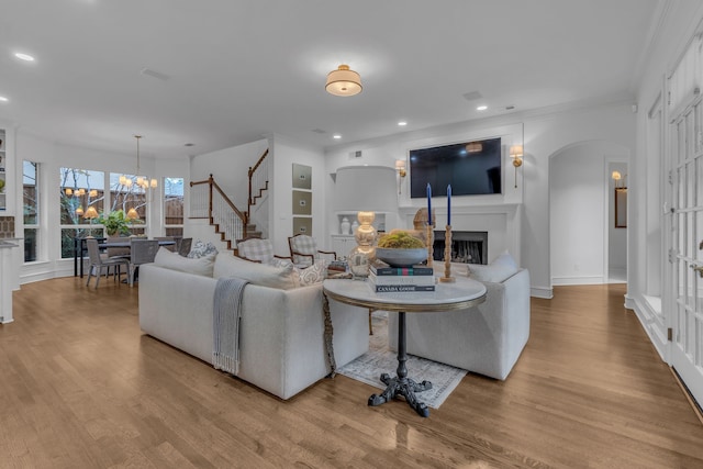 living room featuring light hardwood / wood-style flooring, built in features, and a chandelier