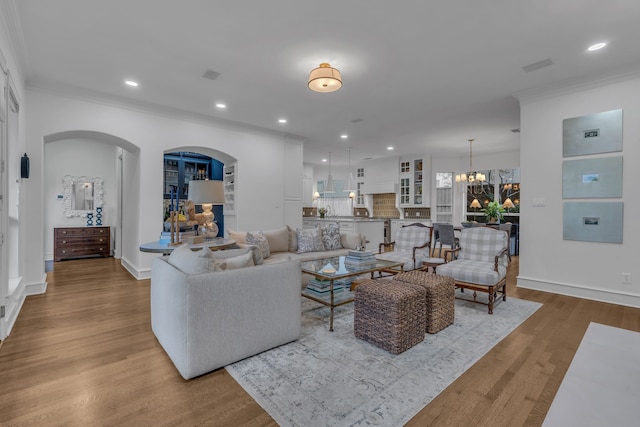 living room with ornamental molding, a chandelier, and light hardwood / wood-style flooring