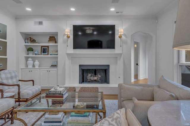 living room featuring hardwood / wood-style floors, built in shelves, and ornamental molding