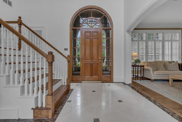 entryway with crown molding and a towering ceiling