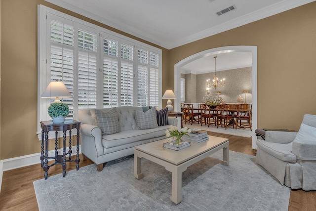 living room with an inviting chandelier, crown molding, and hardwood / wood-style flooring