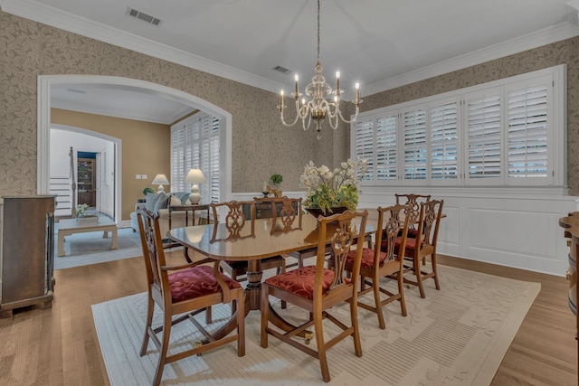 dining area featuring crown molding, an inviting chandelier, and light wood-type flooring