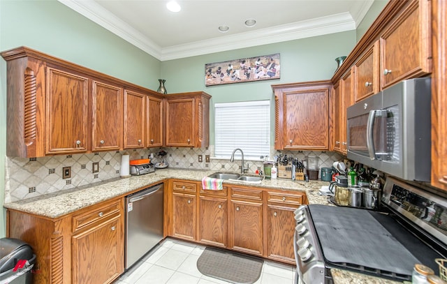 kitchen with light tile patterned flooring, sink, crown molding, appliances with stainless steel finishes, and light stone countertops