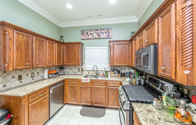 kitchen with appliances with stainless steel finishes, sink, light tile patterned floors, light stone counters, and crown molding