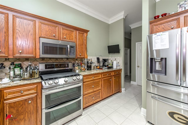 kitchen featuring appliances with stainless steel finishes, tasteful backsplash, light tile patterned floors, light stone counters, and crown molding