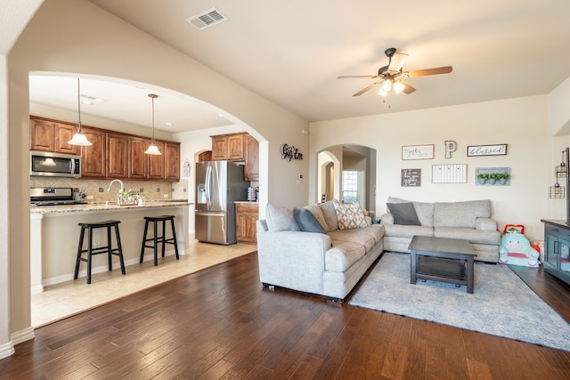 living room with sink, dark wood-type flooring, and ceiling fan