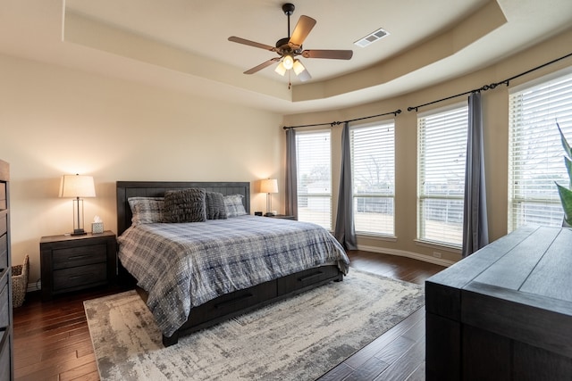 bedroom featuring ceiling fan, dark hardwood / wood-style floors, and a raised ceiling