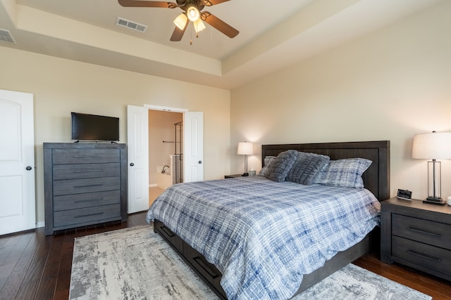 bedroom featuring dark wood-type flooring, ceiling fan, and a tray ceiling