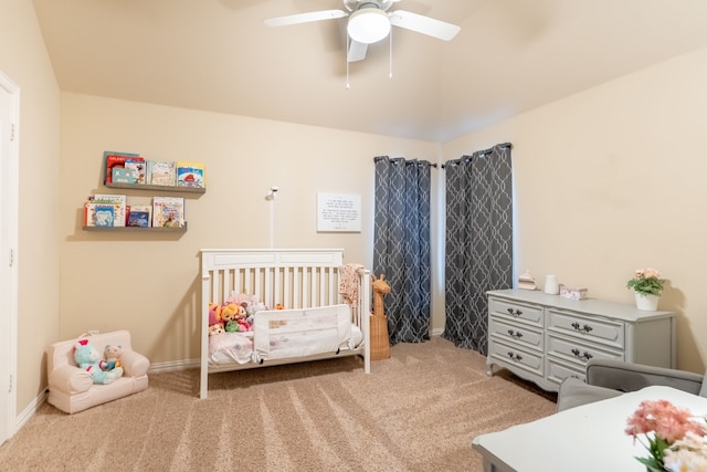 carpeted bedroom featuring ceiling fan and a crib