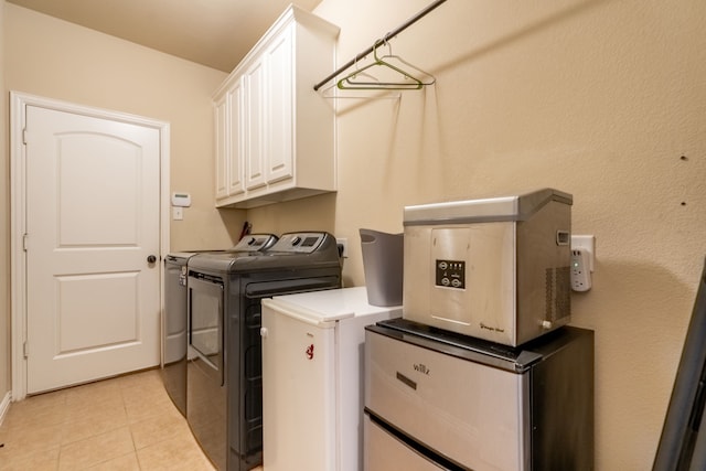 laundry room featuring cabinets, light tile patterned flooring, and washing machine and clothes dryer