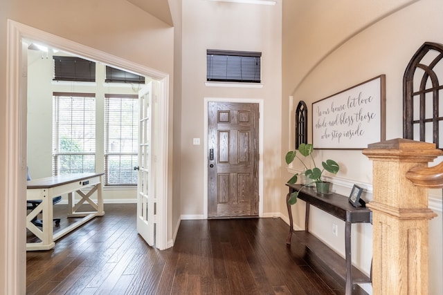 foyer entrance featuring a towering ceiling and dark hardwood / wood-style floors