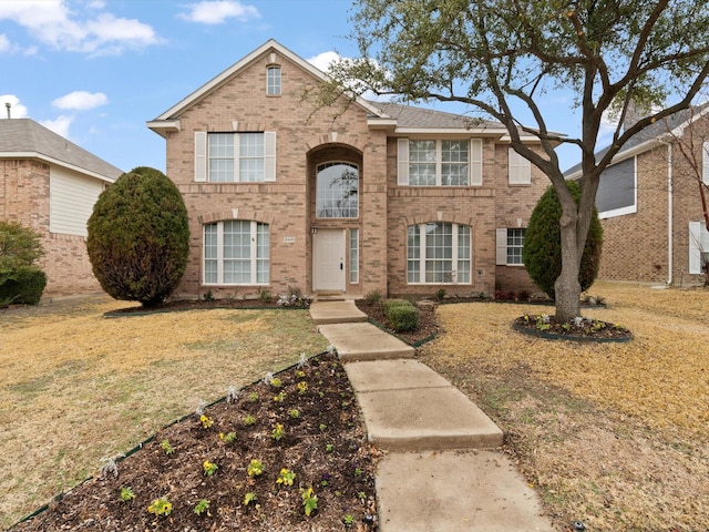 traditional home with brick siding and a front lawn